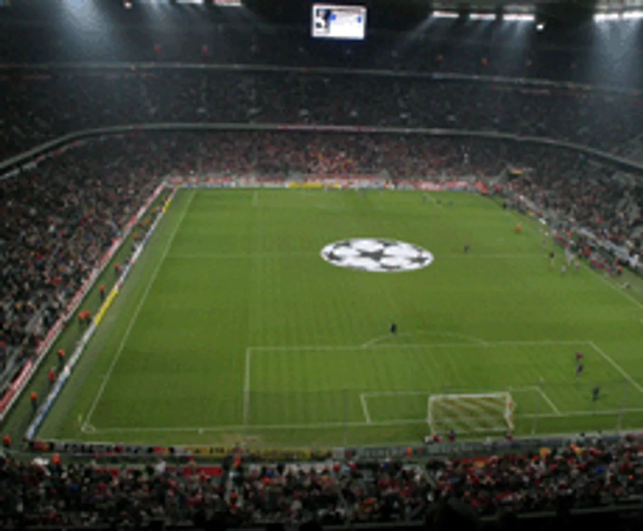 Un stadio di calcio con uno schermo grande e un logo al centro del campo da gioco.