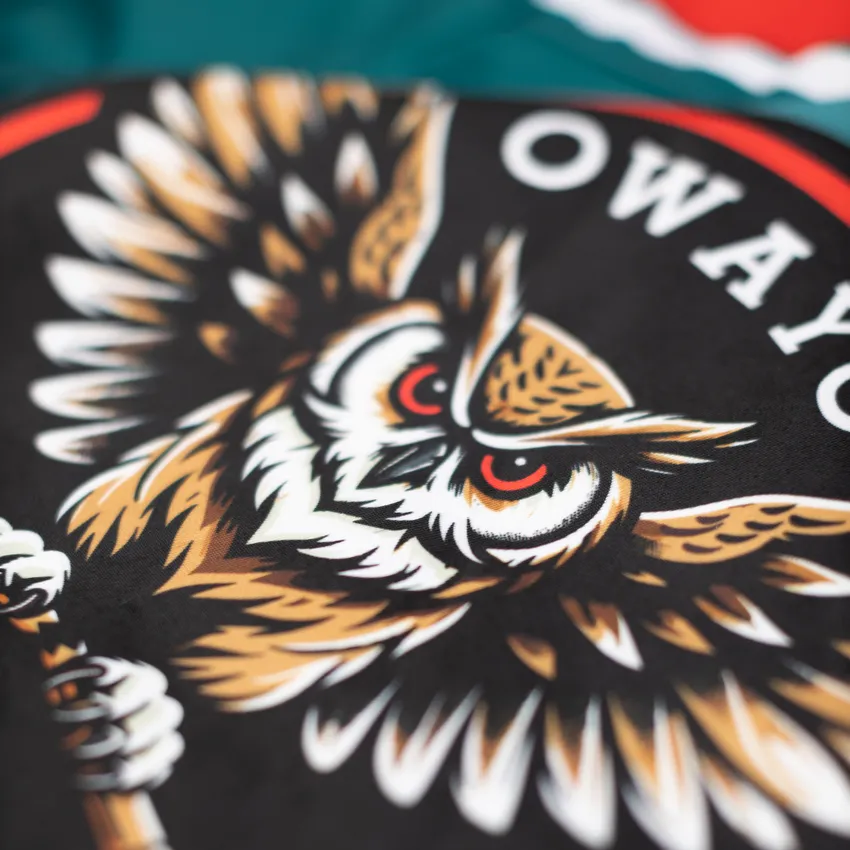 Un design dettagliato e colorato di un motivo di gufo su sfondo nero, presente su un capo sportivo di owayo.