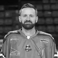 Un uomo con barba indossa una maglia da hockey con vari loghi di sponsor, incluso il logo di owayo.