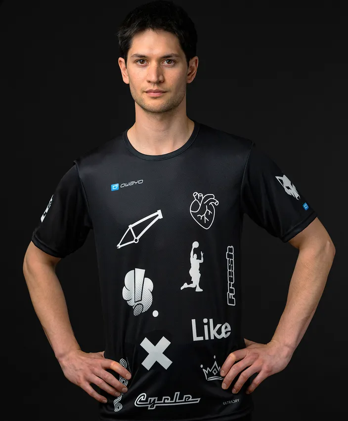 Un uomo indossa una maglietta sportiva nera con vari simboli e loghi bianchi.