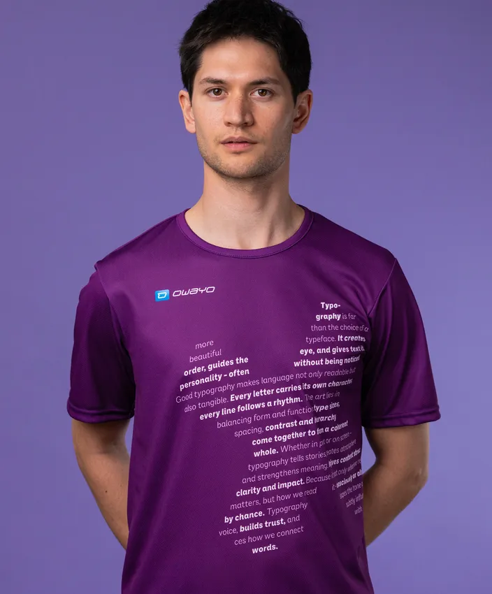 Un uomo indossa una maglietta sportiva viola con testo tipografico sulla parte anteriore, su uno sfondo viola.