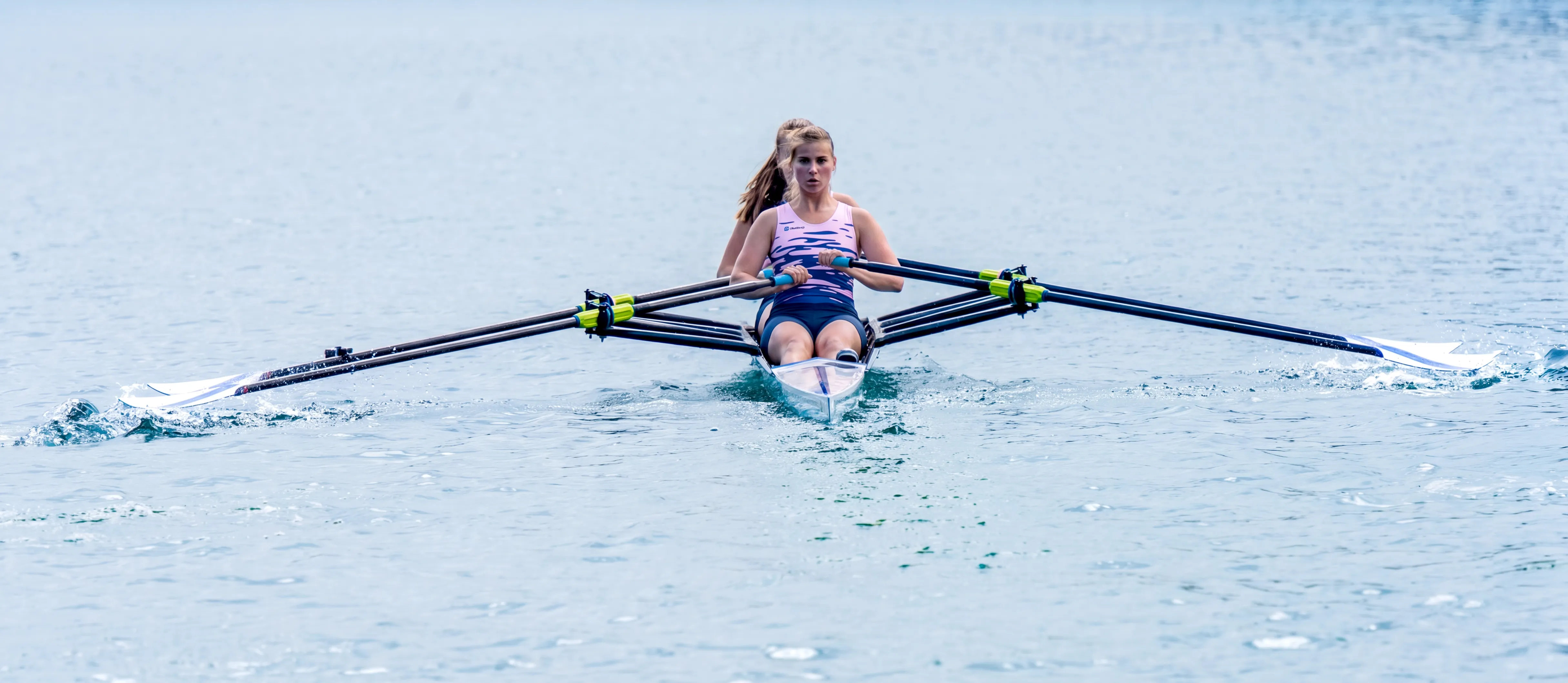 Una rematrice in una barca sta remando su un lago calmo.