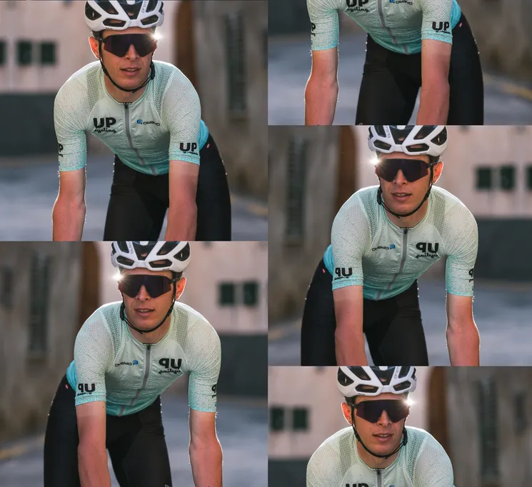 Un ciclista indossa una maglia su misura azzurra con il logo 'UP cycling' e 'owayo' sul petto, che pedala per una strada.